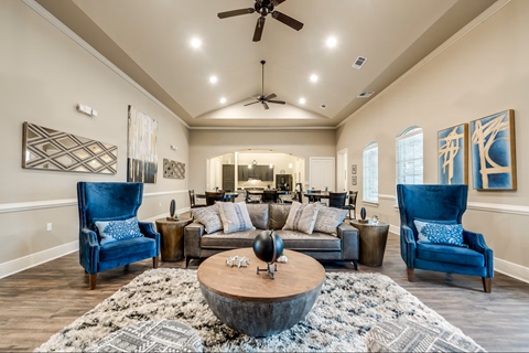 A living room with a large rug and two blue chairs.