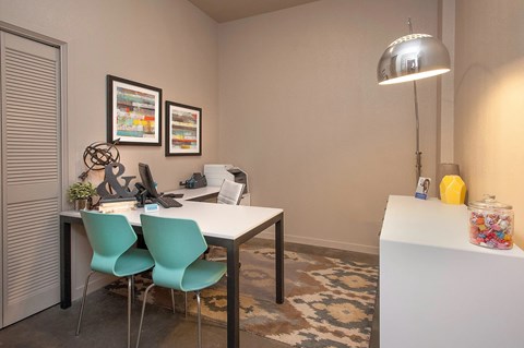 A room with a desk, chairs, and a lamp.