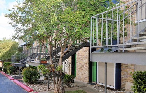A tree in front of a building with a balcony.