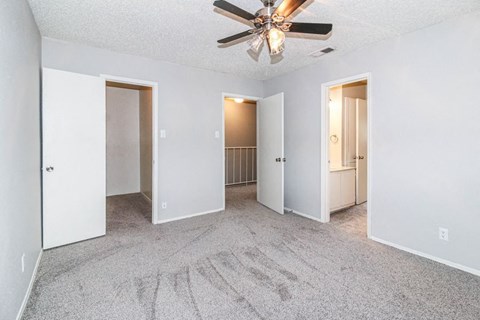 A spacious room with a ceiling fan and carpeted floor.