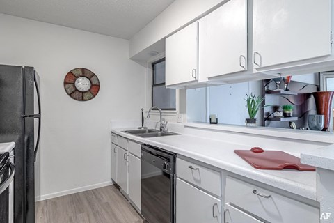A kitchen with white cabinets and a black refrigerator.