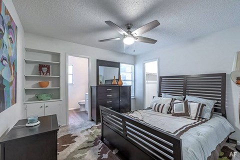 A bedroom with a bed, dresser, and ceiling fan.