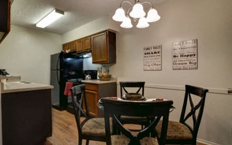 A kitchen with a refrigerator, microwave, and a dining table with chairs.