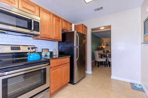 A kitchen with a black refrigerator and stove top oven.