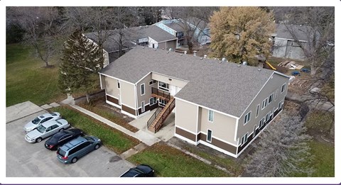A house with a grey roof and a parking lot in front.