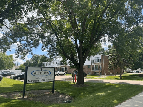 A tree stands in front of a Suite Living apartment complex.