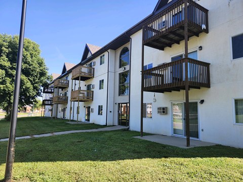 A white building with balconies and a green lawn in front.