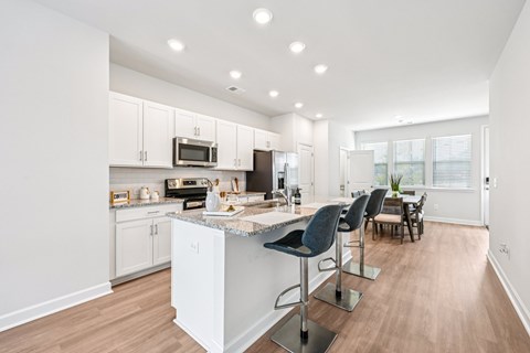 A kitchen with a white island and bar stools.
