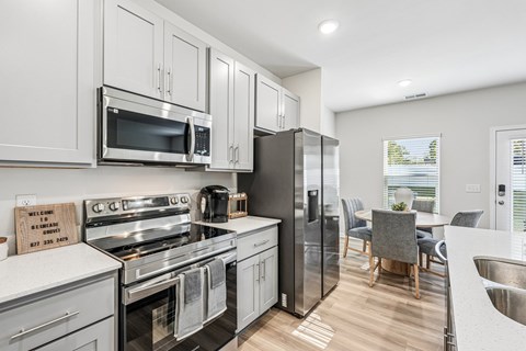 A modern kitchen with stainless steel appliances and a dining area.
