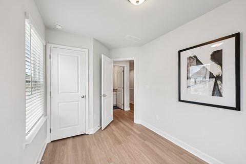 A hallway with a white door and a framed picture on the wall.