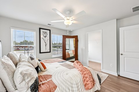 A bedroom with a bed, pillows, a ceiling fan, and a window with blinds.