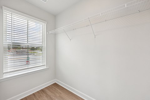 A room with a window and a clothes rack.