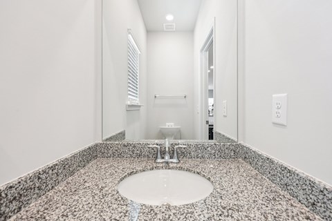A bathroom with a granite counter top and a round sink.