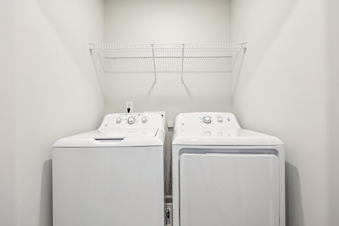 Two white washing machines in a laundry room.