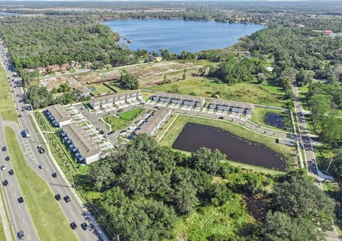 A large building complex is surrounded by a lake and greenery.