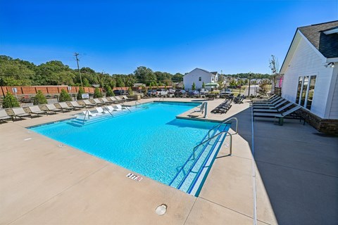 A large swimming pool with a blue tiled edge and a white building to the right.