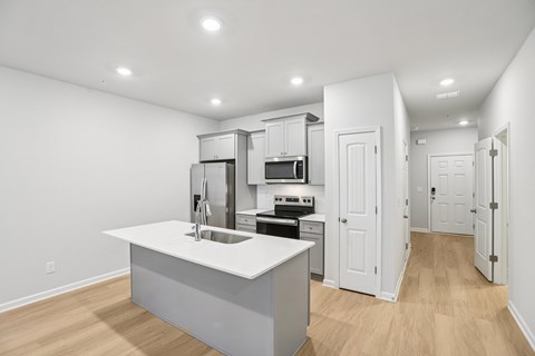 A kitchen with white cabinets and a white island.