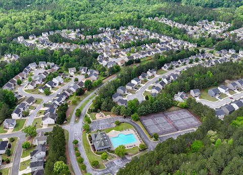 A bird's eye view of a residential area with houses, roads, and a swimming pool.