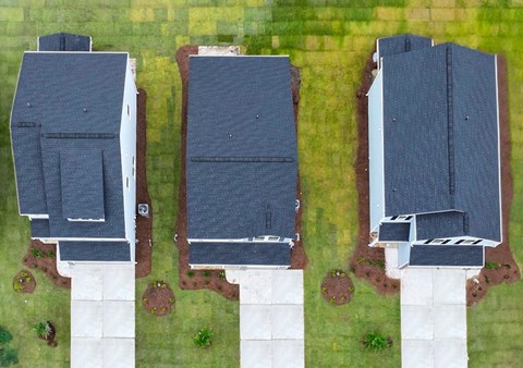 Three houses with grey roofs and white columns.
