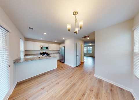 A well-lit kitchen with wooden floors and a chandelier.