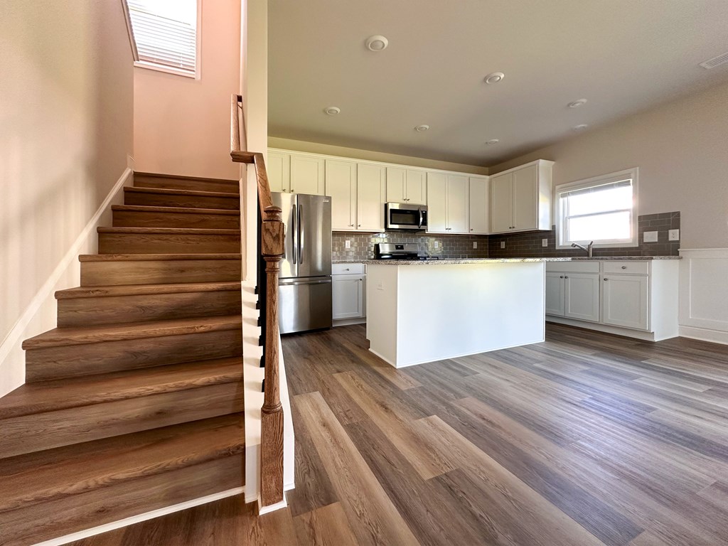A kitchen with a refrigerator, microwave, and cabinets.