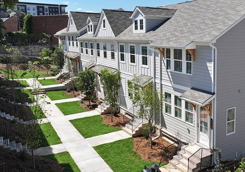 A white house with a grey roof and a green lawn in front.