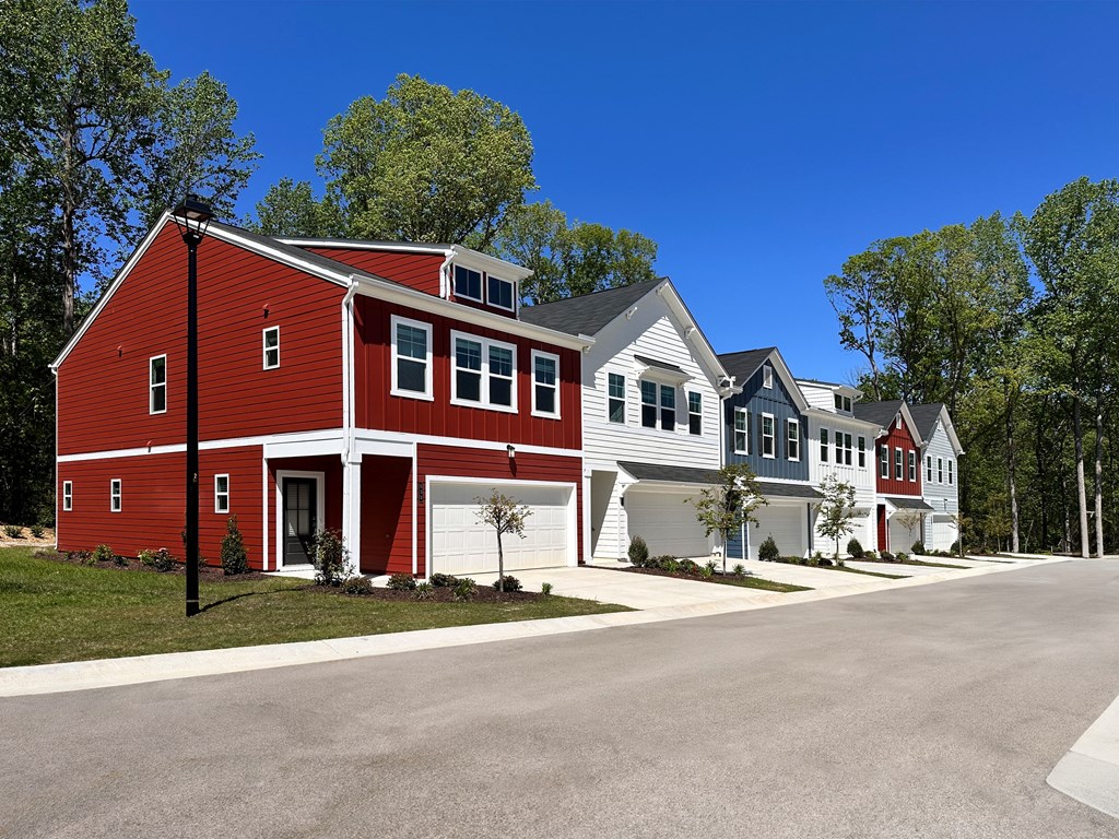 A red barn-like building is in the foreground of a row of houses.