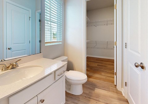 A white toilet sits in a bathroom with a white sink and a white cabinet.
