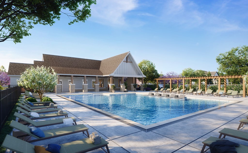 A pool with sun loungers and a building in the background.
