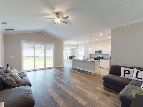 A living room with a grey couch and a ceiling fan.