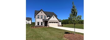A two-story house with a garage and a tree in front.