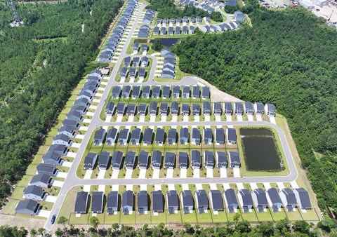 A bird's eye view of a residential area with houses and a pond.
