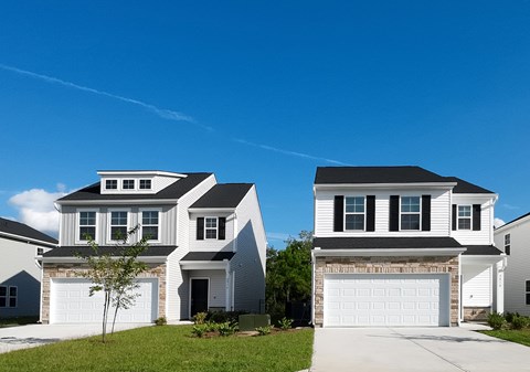 Two houses with garages are situated in a suburban neighborhood.