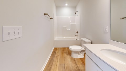 A white bathroom with wood flooring and a white sink.