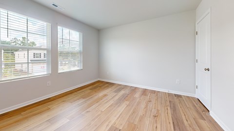 A room with wooden flooring and a white door.