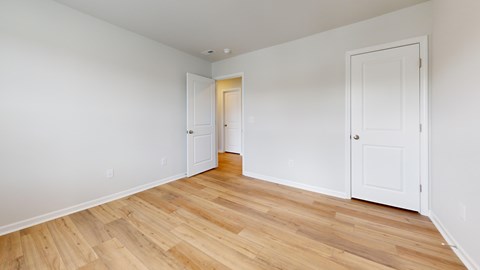 A room with wooden flooring and white walls.