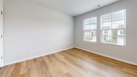 A room with wooden flooring and a window with blinds.