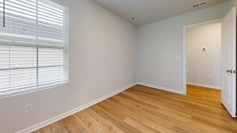 A room with wooden floors and a window with blinds.