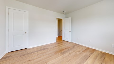 A room with a white door and a white wall with a wooden floor.