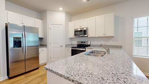 A kitchen with a granite countertop and stainless steel appliances.