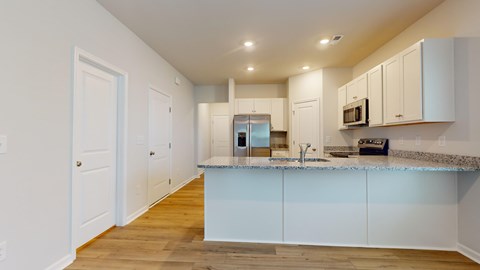 A kitchen with white cabinets and a marble countertop.
