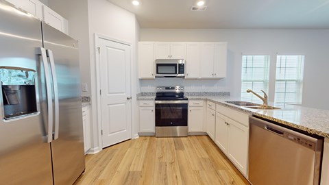 A kitchen with a refrigerator, oven, microwave, dishwasher, and cabinets.