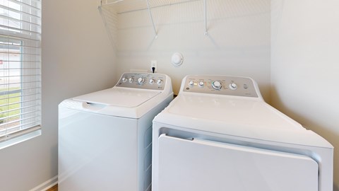 Two white front loading washing machines in a small laundry room.