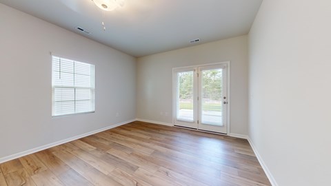 A room with wooden flooring and a sliding glass door.