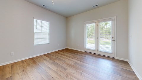 A room with wooden flooring and a sliding glass door.