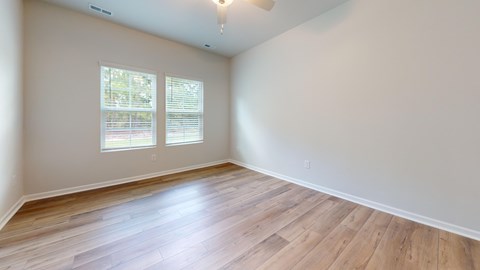 A room with wooden flooring and a window with blinds.