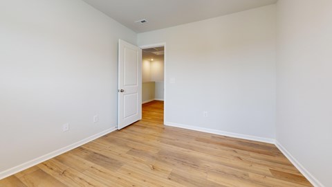 A room with wooden flooring and a white door.