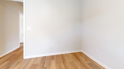 A room with wooden flooring and white walls.