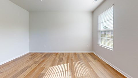 A room with wooden flooring and a window with blinds.