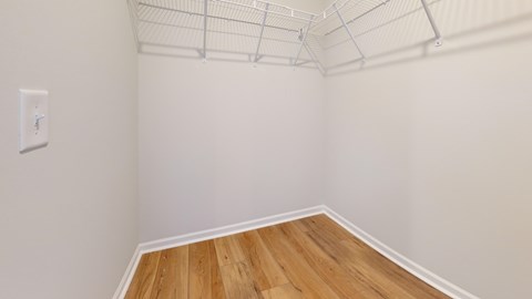 A room with a light switch and wooden flooring.